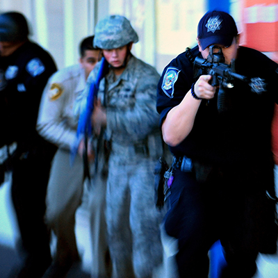A law enforcement team consisting of two North Las Vegas Police Department police officers, one Airman from 99th Security Forces Squadron, one Nevada Highway Patrol officer and one Las Vegas Metro Police Department officer, move quickly as two simulated gunman fire upon students  at Lomie Heard Elementary School, March 28, 2012 during a Multi Assault Counter Terrorism Action Capabilities exercise at Nellis Air Force Base, Nev. The scenario prepared participants to respond to real-word active shooter events. (U.S. Air Force photo by Staff Sgt. William P.Coleman)
